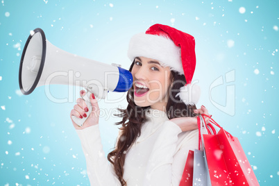 Composite image of festive brunette holding gift bags and megaph