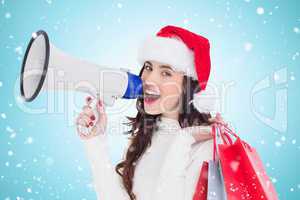 Composite image of festive brunette holding gift bags and megaph