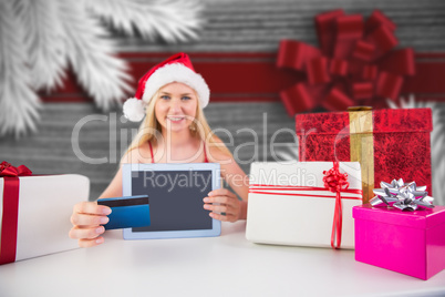 Composite image of festive blonde shopping online with tablet pc