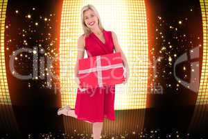 Composite image of stylish blonde in red dress holding gift