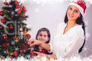 Composite image of mother and daughter hanging christmas decorat
