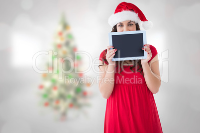 Composite image of festive brunette showing a tablet