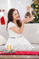 Composite image of happy brunette holding baby shoes at christmas