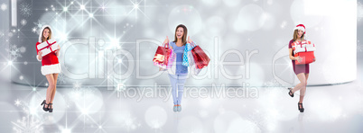 Composite image of festive brunette holding pile of gifts