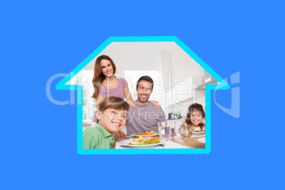 Composite image of family looking at the camera at dinner time
