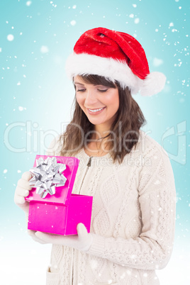 Composite image of smiling brunette opening christmas gift