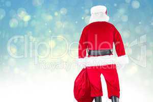 Composite image of rear view of santa claus holding a sack