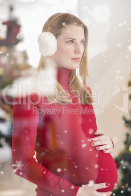Composite image of pretty pregnant woman caressing her belly while standing