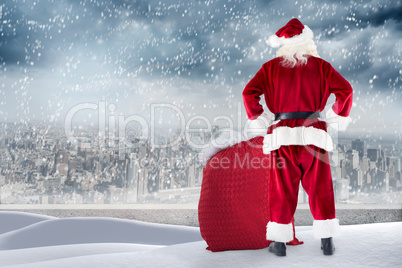 Composite image of santa standing on snowy ledge