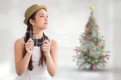 Composite image of happy brunette in hat holding phone