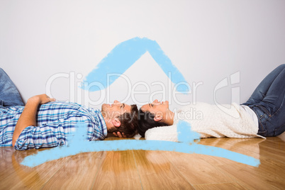 Composite image of young couple lying on floor smiling