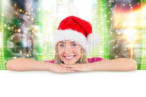 Composite image of festive blonde leaning on large poster