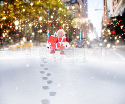 Composite image of santa carrying gifts in the snow