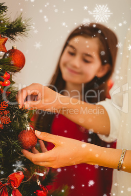 Composite image of woman hanging christmas decorations on tree