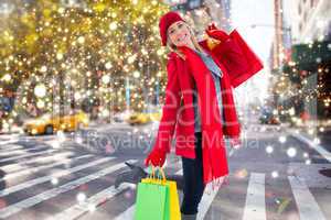 Composite image of happy blonde in winter clothes holding shoppi