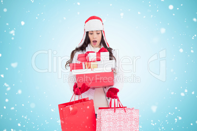 Composite image of surprised brunette in winter clothes holding