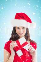 Composite image of festive brunette holding gift