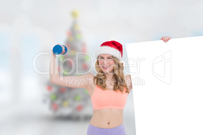 Composite image of festive fit blonde smiling at camera holding