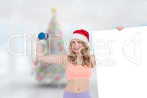 Composite image of festive fit blonde smiling at camera holding