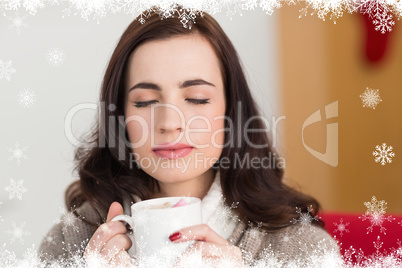 Composite image of brunette enjoying a hot chocolate with marshm