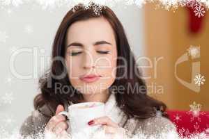 Composite image of brunette enjoying a hot chocolate with marshm