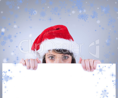 Composite image of festive brunette holding a poster