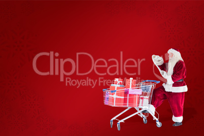 Composite image of santa pushes a shopping cart while reading