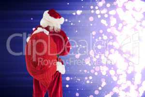 Composite image of santa is holding his bag in one hand