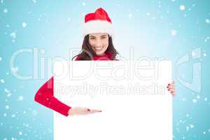 Composite image of smiling brunette in santa hat pointing white