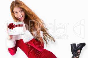 Composite image of festive redhead holding a gift