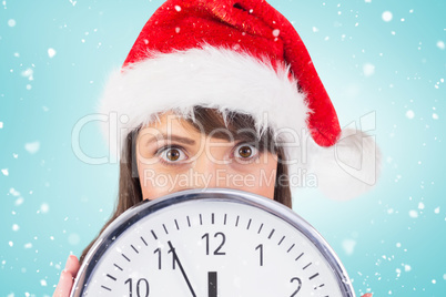 Composite image of portrait of a festive brunette holding a cloc