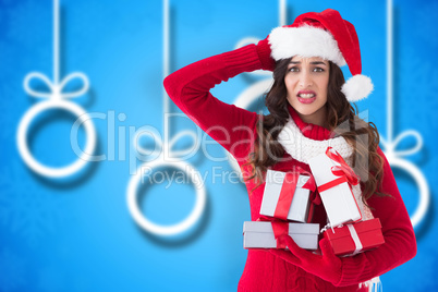 Composite image of stressed brunette in santa hat holding gifts