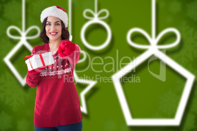 Composite image of happy brunette in santa hat offering gift