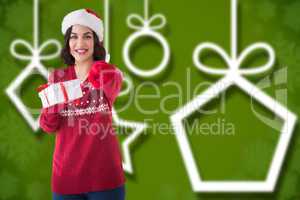 Composite image of happy brunette in santa hat offering gift
