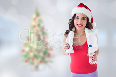 Composite image of festive fit brunette holding bottle