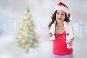 Composite image of festive fit brunette holding bottle