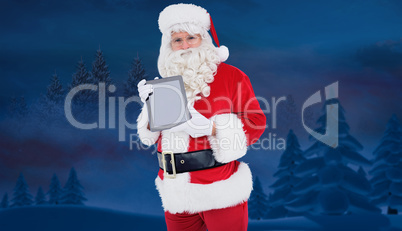 Composite image of happy santa showing digital tablet