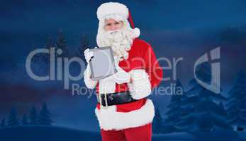 Composite image of happy santa showing digital tablet