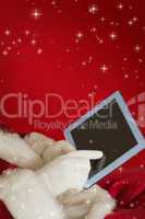 Composite image of santa using tablet on the armchair