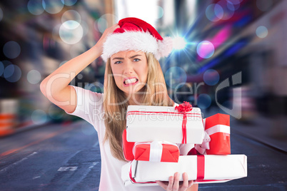 Composite image of festive blonde holding pile of gifts