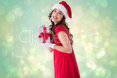 Composite image of festive brunette showing gift