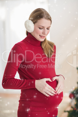 Composite image of pregnant woman making a heart with her hands on her belly