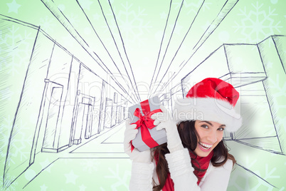 Composite image of happy brunette in santa hat holding gift