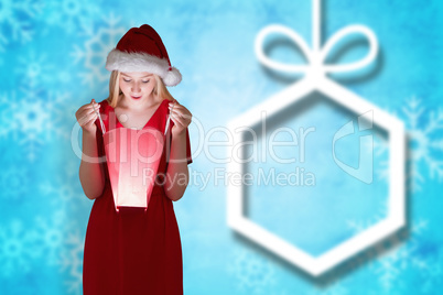 Composite image of festive blonde opening a gift bag