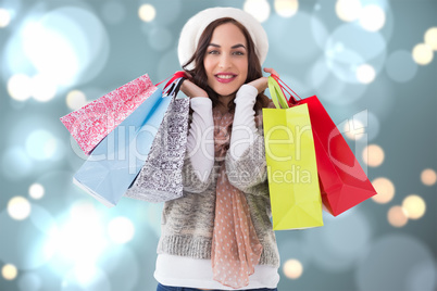 Composite image of brunette in winter clothes with shopping bags