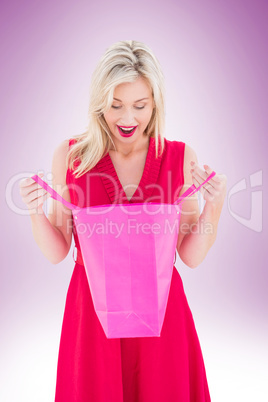 Stylish blonde in red dress opening gift bag