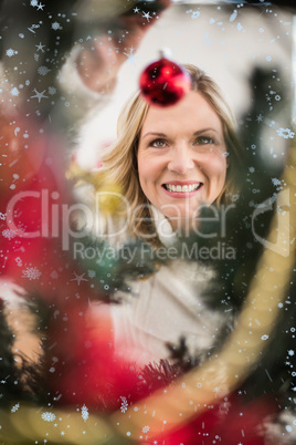 Composite image of festive blonde hanging bauble on christmas tree