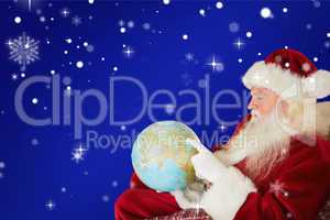 Composite image of father christmas pointing to globe