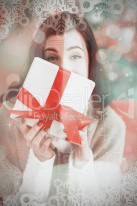 Composite image of brunette showing gift on the couch at christm