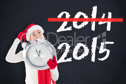 Composite image of festive blonde holding a clock